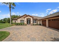 Beautiful home featuring a three-car garage, stone accents, manicured landscaping, and a tile driveway at 11729 Newberry Grove Loop, Riverview, FL 33579