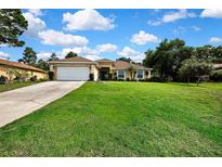 Beautiful single-story home with a well-manicured lawn, attached garage and neatly landscaped garden beds at 12411 Talpa St, Spring Hill, FL 34608