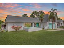 Charming single-Gathering home with a well-manicured lawn, mature landscaping, and a lovely splash of color on the doors at 3519 Richboro Dr, Holiday, FL 34691