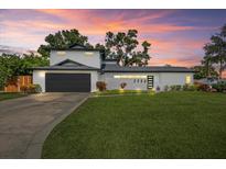 Contemporary home featuring a well-manicured lawn and an attached garage against a dramatic sunset at 3956 Versailles Dr, Tampa, FL 33634