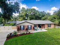 Charming brick home with manicured lawn, lovely landscaping, and inviting front porch with colorful chairs at 4205 Helene Pl, Valrico, FL 33594