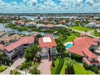 Expansive aerial view of a waterfront home with a red tile roof and a sparkling blue pool, surrounded by lush landscaping at 6107 Marbella Blvd, Apollo Beach, FL 33572