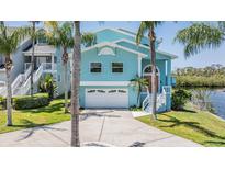 Charming aqua home featuring a two-car garage, well-kept lawn, and attractive landscaping at 6186 Seaside Dr, New Port Richey, FL 34652