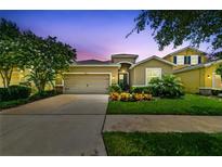 Inviting single-Gathering home featuring a manicured lawn, colorful flowerbeds, and a two-car garage at 6467 Seasound Dr, Apollo Beach, FL 33572