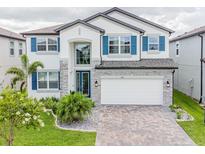Beautiful two-story home featuring stone accents, blue shutters, and a paved driveway at 7700 Bronze Oak Dr, Wesley Chapel, FL 33545