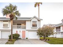 Charming two-story home boasts a pink door, garage, palm trees, and well-maintained landscaping at 112 Sun Isle Cir # 112, Treasure Island, FL 33706