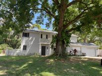 Charming two-story home with mature tree in front yard, features a balcony and attached garage at 14803 Tulip Dr, Tampa, FL 33613