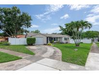 Charming single-story home with a well-manicured lawn, circular driveway, and white picket fence at 1806 11Th Sw St, Largo, FL 33778