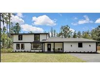Charming two-story home with white facade, black trim, and a well-manicured lawn at 19003 Cedar Ln, Lutz, FL 33548