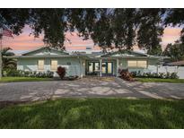 Charming light blue home featuring double doors, a brick driveway and mature landscaping at 316 Cedar Ln, Largo, FL 33770