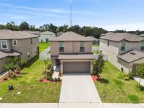 Two-story home featuring a two-car garage, manicured lawn, and tasteful landscaping at 36412 Garden Wall Way, Zephyrhills, FL 33541