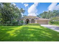 Beautiful single-story home featuring a well-manicured lawn, mature landscaping, and an inviting neutral-toned facade at 511 Duque Rd, Lutz, FL 33549