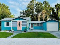 Charming blue home with a pink front door, well-manicured lawn, and a detached garage at 5130 Pine Grove S Ter, Gulfport, FL 33707