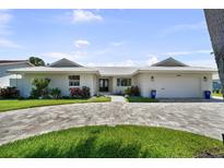 Charming single-story home with a well-manicured lawn and circular brick driveway, showcasing curb appeal at 5884 51St S St, St Petersburg, FL 33715