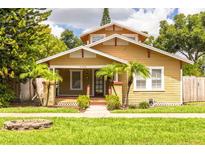 Charming home featuring a cozy front porch, well-maintained lawn, and lush landscaping with mature trees at 6408 N Central Ave, Tampa, FL 33604
