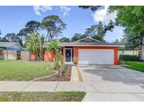 Charming single-story home featuring a lush lawn, vibrant landscaping, and an attached two-car garage at 6865 Circle Creek Dr, Pinellas Park, FL 33781