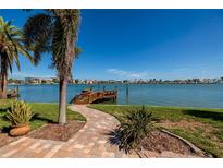 Beautiful waterfront backyard featuring a wooden dock, lush landscaping, and serene water views at 208 Bath Club N Blvd, North Redington Beach, FL 33708