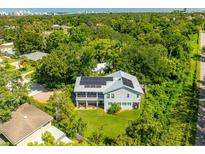Stunning aerial view of home featuring solar panels and lush greenery in a quiet neighborhood with water views at 321 Barbara Cir, Belleair, FL 33756