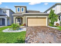 Inviting two-story home featuring manicured lawn and a tan two car garage at 33854 Floating Heart Ct, Wesley Chapel, FL 33545