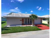 Charming single-story home featuring a well-manicured lawn, red driveway, and a decorative palm tree at 5390 Magnolia N Trl, Pinellas Park, FL 33782