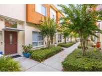 Inviting townhome exterior with a walkway lined with manicured landscaping and trees leading to the front door at 851 3Rd Ave N, St Petersburg, FL 33701