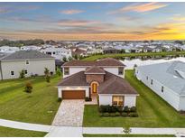 Stunning aerial view of a home in a lakeside community, showcasing the brick driveway and two-story design at 8612 Ivy Stark Blvd, Wesley Chapel, FL 33545