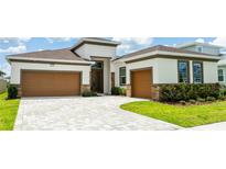 Inviting home featuring a two-car garage, brick accents, and manicured landscaping at 8749 Drummer Plank Dr, Wesley Chapel, FL 33545