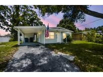 Charming single-story home with gray exterior, covered parking, and an American flag at 10215 N 23Rd St, Tampa, FL 33612