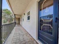 Hallway view to unit 310, featuring metal railings, tan exterior, and a black front door at 11485 Oakhurst Rd # 310, Largo, FL 33771
