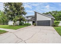 Charming home with an attached garage, manicured lawn, and mature trees creating curb appeal at 1222 Rainbrook Cir, Valrico, FL 33596
