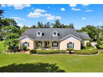 Charming one-story home boasting a well-manicured lawn, green shutters, and a welcoming front porch at 13321 Lewis Raulerson Rd, Dover, FL 33527