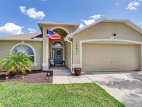 Welcoming home front with a well manicured lawn, an American flag, and a two car garage at 24811 Gun Smoke Dr, Land O Lakes, FL 34639