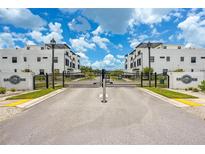 Gated community entrance featuring modern white townhomes under a bright blue sky at 6206 64Th N Way, Pinellas Park, FL 33781