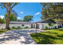 Charming single-story home with a circular driveway, manicured lawn, and lush landscaping at 8010 W Hiawatha St, Tampa, FL 33615