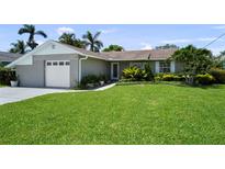 Charming single-story home with a well-manicured lawn and tropical landscaping, and a gray brick facade at 8718 Tahiti Ln, Tampa, FL 33615