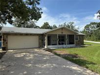 Close-up of a cozy home featuring stone siding, an attached garage, and a welcoming screened front porch at 9171 Vicksburg Rd, Spring Hill, FL 34608