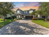 Beautiful two-story home featuring a paver driveway, lush landscaping, and a welcoming front porch at 12121 Rustic River Way, Tampa, FL 33635
