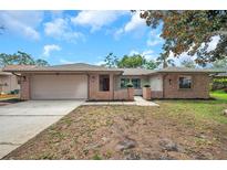 Charming single-story brick home featuring a spacious driveway and attached two-car garage at 1363 Cottage Grove Rd, Tarpon Springs, FL 34689