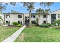 Inviting two-story condo with charming exterior, lush landscaping, and sidewalk leading to the entrance at 326 Moorings Cove Dr # 2B, Tarpon Springs, FL 34689