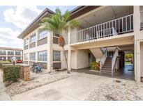 Inviting two-story condo building with a covered entrance, stairs, palm tree, and patio chairs for relaxing outdoors at 5111 Amulet Dr # 208, New Port Richey, FL 34652