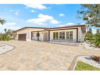 Charming single-story home featuring a meticulously landscaped front yard and brick driveway at 6400 Mockingbird S Way, St Petersburg, FL 33707