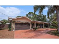 Charming home exterior featuring a two-car garage, covered porch, and mature landscaping at 7802 134Th St, Seminole, FL 33776