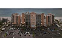 Wide shot of a beachfront condo building, parking lot, and sandy beach at 880 Mandalay Ave # C513, Clearwater Beach, FL 33767