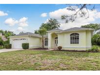 Charming single-story home with a well-manicured lawn and attached two-car garage at 1156 Ridgegrove W Dr, Palm Harbor, FL 34683
