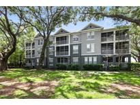 Charming condo building with screened-in porches surrounded by lush green lawns and mature trees at 1201 High Hammock Dr # 302, Tampa, FL 33619