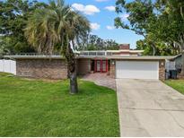 Charming single-story home featuring stone accents, a two-car garage, and a lush green lawn with a mature palm tree at 1309 Eastfield Dr, Clearwater, FL 33764