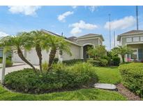 Inviting home exterior featuring a well-manicured lawn and lush tropical landscaping at 13524 Circa Crossing Dr, Lithia, FL 33547
