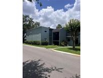 A two-story building featuring manicured landscaping, and a grey painted exterior, under a cloudy sky at 2850 Somerset Park Dr # 203, Tampa, FL 33613