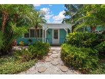 Charming home entrance surrounded by lush tropical landscaping and a welcoming covered porch at 301 Cevera Dr, Dunedin, FL 34698