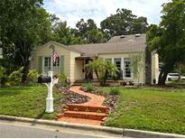 Charming yellow two-story home with a brick walkway and American flag displayed at 3516 W Santiago St, Tampa, FL 33629